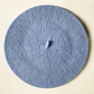 Top-down view of a light blue cashmere-like wool beret with a center decorative stem