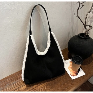 Detail of black lambskin tote bag with white plush trim on a cozy wooden table