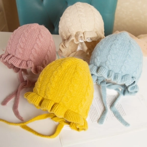 Detailed view of four colors of ruffled knit baby hats with ribbons in a soft display