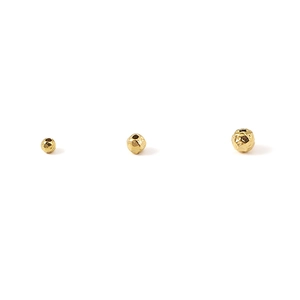 Close-up of three golden hammered stainless steel beads for DIY jewelry making