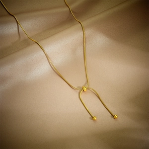 Layered gold snake chain necklace with adjustable bead on elegant silk background