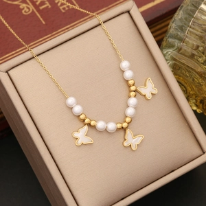Elegant gold butterfly necklace with white shell pendants and pearls on a jewelry box
