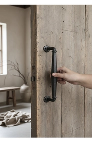 Close-up of black cast iron handle with industrial texture mounted on rustic wood door