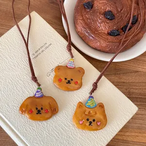 Collana croissant in pelle con ciondoli orso cane e gattino posata su un libro
