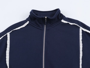 Détail d'un sweat bleu marine avec dentelle blanche brodée et fermeture éclair argentée