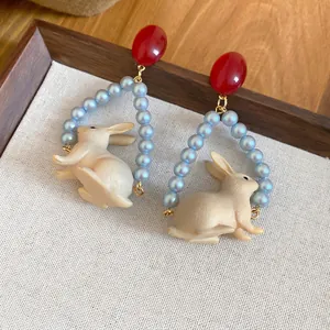 Boucles d'oreilles lapin avec clous rouges et créoles en perles bleues sur plateau