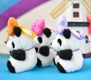 Side detail view of three adorable panda plush keychains featuring vibrant colorful bows