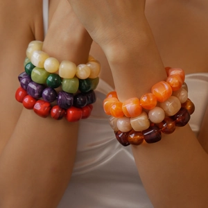 Close-up of stacked acrylic beaded bracelets in vibrant colors on a model arm