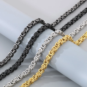 Detail of braided Byzantine chains in black, silver, and gold finishes on grey props