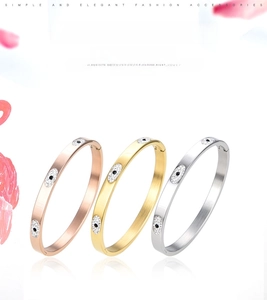 Detailed view of three stainless steel evil eye bangles in rose gold, gold, and silver finish