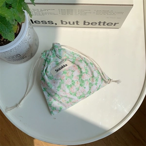 Detail of floral cloth drawstring pouch showing green flower patterns and rope closure