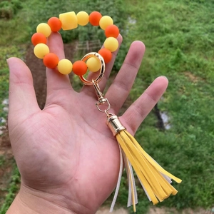 Portachiavi in silicone con perle gialle e arancioni e nappa in PU tenuto in mano