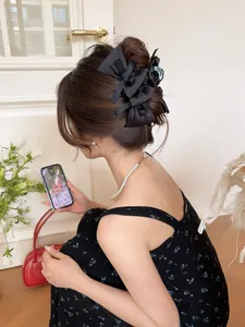 Detail view of a black satin bow hair claw clip styled in an elegant updo hairstyle