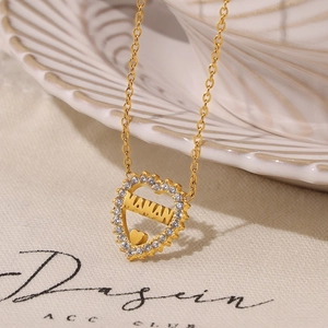 Gold heart necklace with MAMAN lettering and zircon inlay on elegant ceramic display