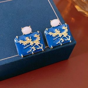 Detail of vintage blue enamel earrings with gold floral pattern and pink gemstones
