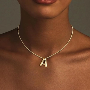 Close-up of 18K gold plated puffy letter A pendant on a thin beaded chain for women