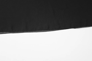 Close-up of the fine stitching and smooth hem detail on a black sheer chiffon blouse