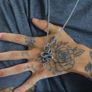 Silver stainless steel snake pendant necklace worn by a model over a grey T-shirt