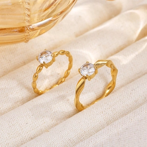 Golden Moebius twisted and braided rings set with sparkling zircon on soft fabric