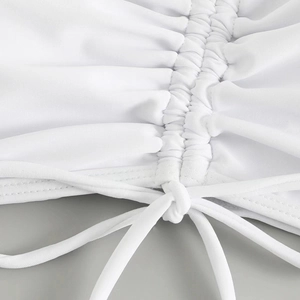 Detail view of the ruched texture and adjustable drawstring on white swimwear fabric