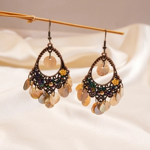Macro view of bohemian drop earrings with vintage bronze texture and natural shells