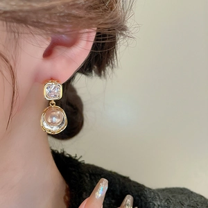 Detailed close-up of a vintage golden earring featuring square zircon and champagne pearl