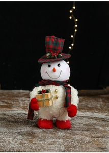 Close-up of a plush Christmas snowman with red-green plaid hat holding a golden gift box