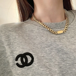Detailed view of a gold Cuban link chain necklace with a rectangular metal plate on neck