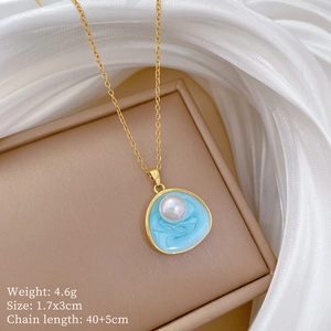 Détail du collier en titane doré avec pendentif ondulé bleu et perle sur boîte