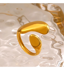 Close-up of a golden irregular fluid ring with a polished mirror finish on textured glass