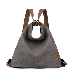 Versatile grey canvas backpack and handbag with brown leather straps on white background