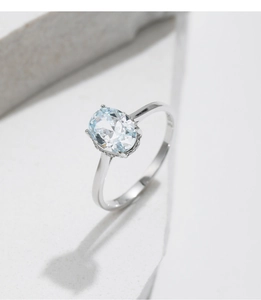 Macro detail of oval cut clear gemstone ring set in polished silver on stone blocks