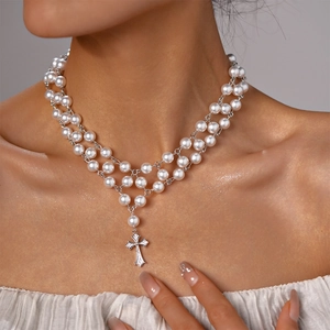 Détail d'un collier de perles à double rang avec pendentif croix en strass sur modèle