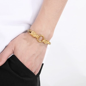 Detail of dragon head clasps on a golden stainless steel bracelet worn by a male model