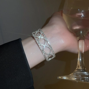 Close-up of sparkling silver hollowed-out rhinestone bracelet worn at a social event