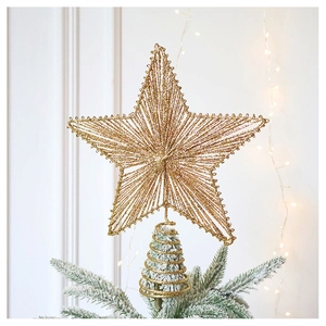 Close-up of sparkling gold glitter star topper mounted on a snowy Christmas tree