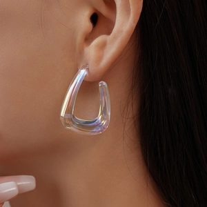 Macro detail of a iridescent acrylic geometric U-shaped earring worn by a model