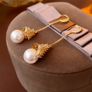 Détail macro de boucles d'oreilles pendantes en perles avec chaîne dorée et zircons
