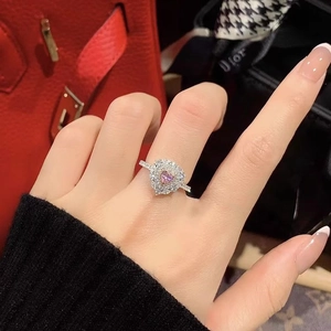 Primo piano di un anello a cuore con cristallo rosa e diamanti sul dito di una donna