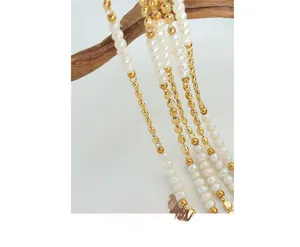 Detail of freshwater pearls and golden beads on a textured wooden branch background