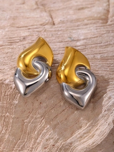 Macro view of two-tone twisted heart earrings in polished gold and silver steel finish