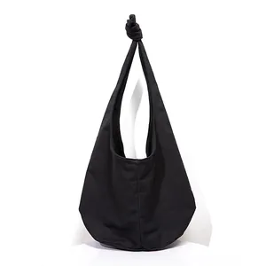 Detail of minimalist black canvas shoulder bag showing the unique knotted handle design