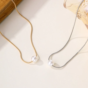 Minimalist gold and silver pearl necklaces with pendants on a decorative tray