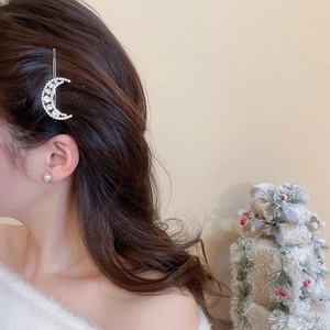 Detailed view of silver moon hair clip with rhinestones worn on long dark hair