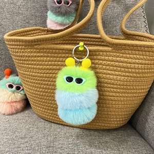 Detail van een kleurrijke rups pluche sleutelhanger met bril op een geweven tas