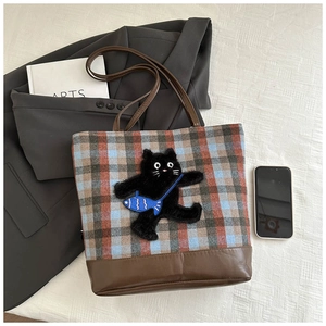 Detail of checkered plaid tote bag with cat embroidery and dark brown leather base