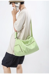 Détail du sac de sport vert clair avec large bandoulière et poche zippée sur modèle
