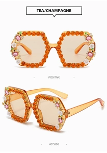 Close-up of tea champagne sunglasses with orange rhinestones and floral bee accents