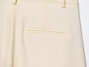 Gros plan détaillé du pantalon crème à taille haute montrant la couture de la poche
