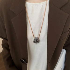 Detail of silver shell pendant with radial textures on an orange woven necklace cord